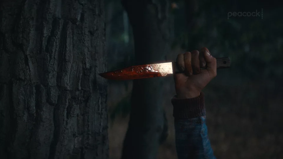 A hand holding a knife outside at night